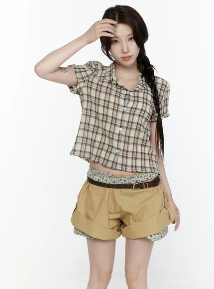 Plaid Button-Up Shirt IL521 Beige front shot on model with braided hair and hands on hips, cropped plaid button-up shirt with open collar, layered over floral top with belted khaki shorts