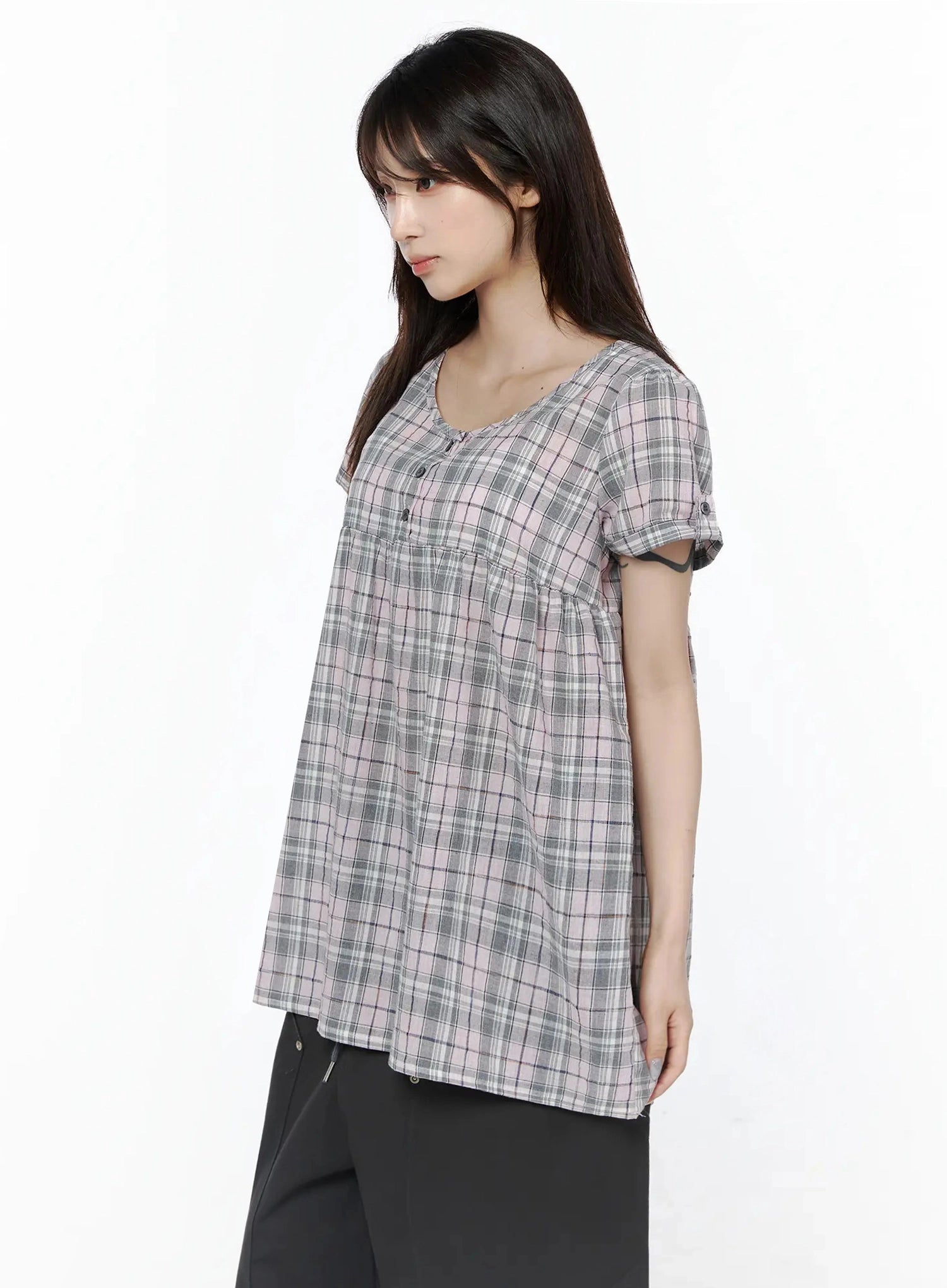 Plaid Cuffed Sleeve Babydoll Dress IL502 Pink side shot on model with relaxed arms showing A-line flare from empire seam and cuffed short sleeves, paired with black pants