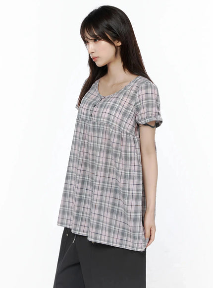 Plaid Cuffed Sleeve Babydoll Dress IL502 Pink side shot on model with relaxed arms showing A-line flare from empire seam and cuffed short sleeves, paired with black pants
