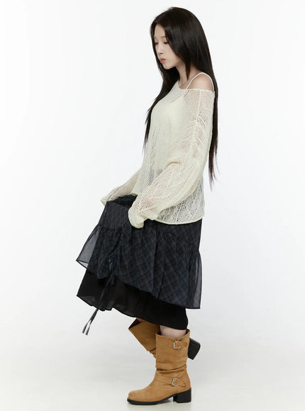 Plaid Layered Midi Skirt IL522 Black full-length side shot on model looking down styled with cream open-knit sweater skirt hem lifted slightly showing layered construction tan boots