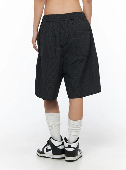 Plaid Nylon Shorts CU523 Black back close-up on model, showing rear patch pockets and elastic waistband of wide-leg grid nylon shorts