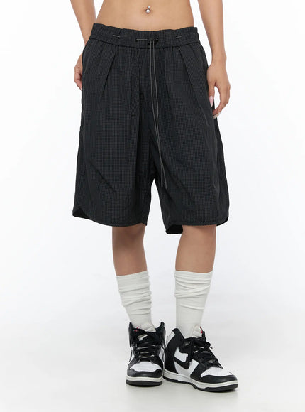Plaid Nylon Shorts CU523 Black front waist-down shot on model with sneakers, wide-leg silhouette and drawstring elastic waistband visible