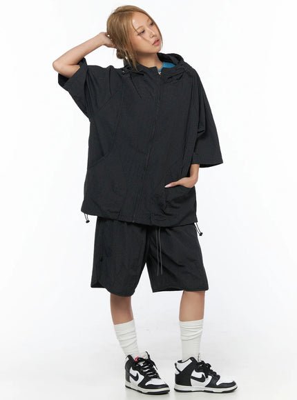 Plaid Nylon Shorts CU523 Black full-body front shot on model styled with matching black grid hooded zip jacket, blue tee, and sneakers