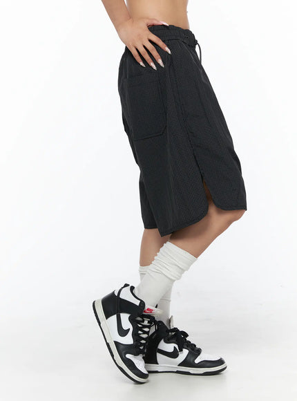 Plaid Nylon Shorts CU523 Black side close-up on model, showing cargo side pocket, drawstring waist, and grid-texture nylon fabric detail