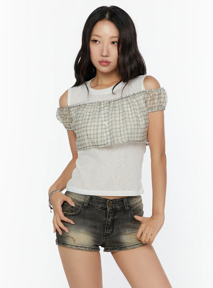 Plaid Off-Shoulder Crop Top CU526 Beige three-quarter front shot on model, beige plaid ruffle overlay with button placket over sheer white knit cropped base, cold-shoulder cutouts, styled with distressed denim shorts