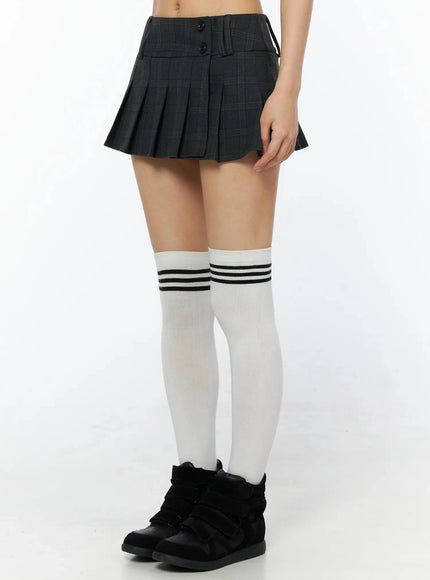 Plaid Pleated Mini Skirt IL516 Dark gray side-angle shot on model showing pleated hem silhouette with white over-the-knee striped socks and black sneakers