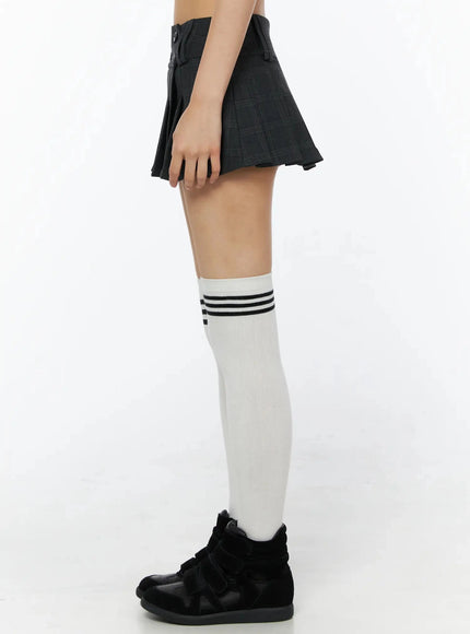 Plaid Pleated Mini Skirt IL516 Dark gray side shot on model showing pleat depth and button closure profile with white knee-high socks and black sneakers