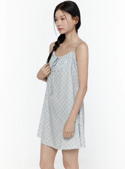 Plaid Shirred Cami Mini Dress IL506 Light blue side model shot model touching hair showing ruched neckline bow tie and flowy lightweight fabric drape