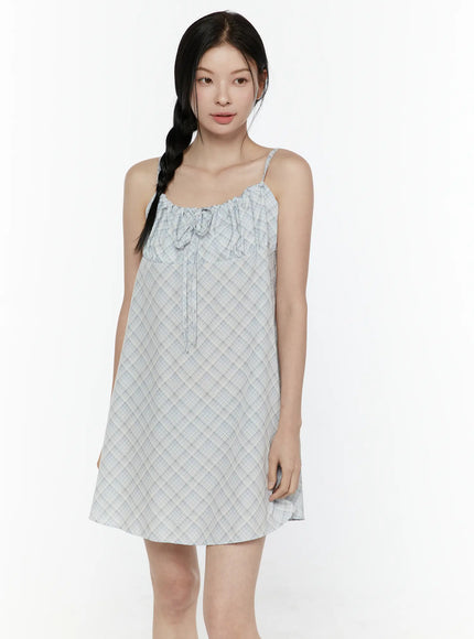Plaid Shirred Cami Mini Dress IL506 Light blue front model shot hands clasped at waist showing full ruched bust panel and relaxed boxy fit with white socks