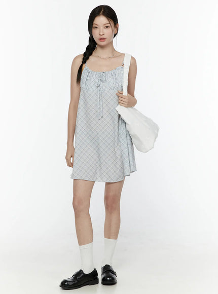 Plaid Shirred Cami Mini Dress IL506 Light blue front full-body model shot styled with white tote bag and pearl necklace standing upright with white socks and loafers