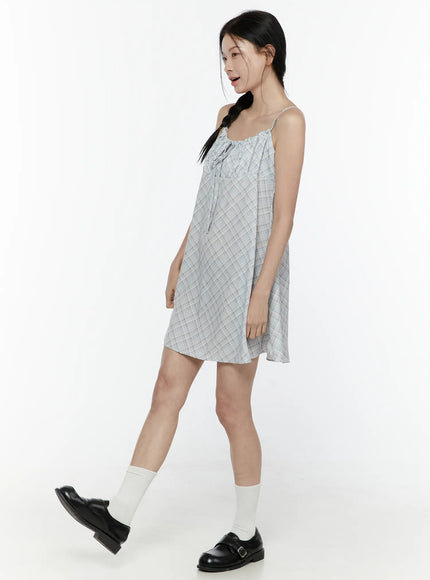 Plaid Shirred Cami Mini Dress IL506 Light blue side model shot model walking pose showing flowy A-line hem and spaghetti straps with white socks and loafers