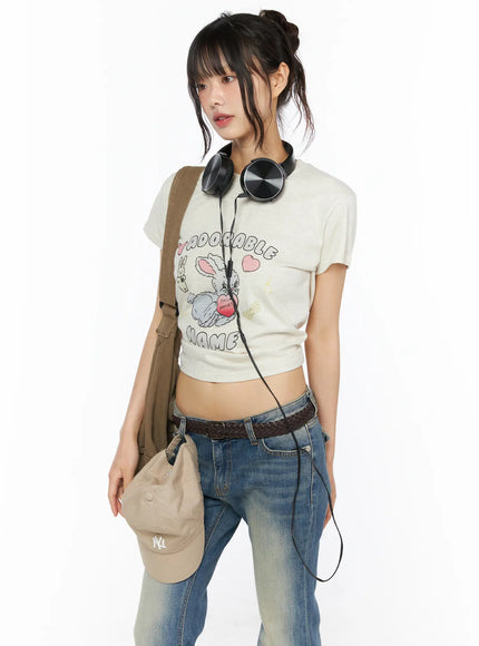 LEWKIN Playful Print Cropped T-Shirt CU530 cream three-quarter front shot on model with headphones bag and jeans Y2K street style