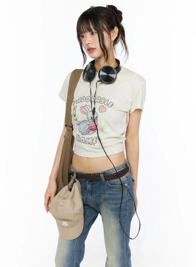 LEWKIN Playful Print Cropped T-Shirt CU530 cream three-quarter front shot on model with headphones bag and jeans Y2K street style