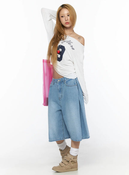 Pleated Denim Jorts CL528 light blue three-quarter front shot on model styled with white off-shoulder top and pink tote arm raised pose