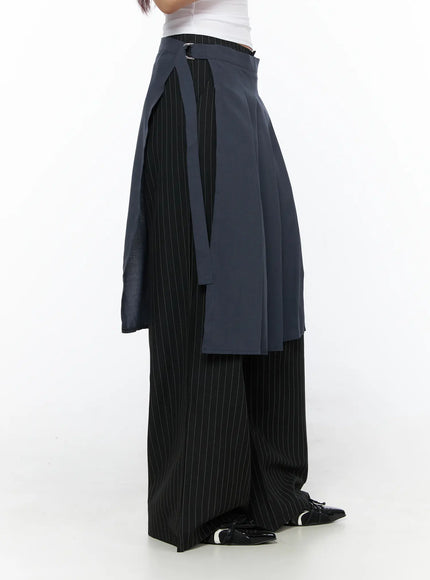 Pleated Midi Wrap Skirt CL513 navy blue side shot model showing open wrap silhouette with pleated navy panel over black pinstripe wide-leg trousers and black patent loafers