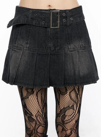 Pleated Mini Skirt And Belt Set CL522 Black close-up detail shot showing metal rectangular buckle, eyelet grommets, washed denim fabric, and box pleats