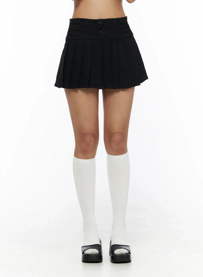Pleated Mini Skirt CL503 Black front close-up on model showing triple-button ruched waistband and knife pleats with white knee socks