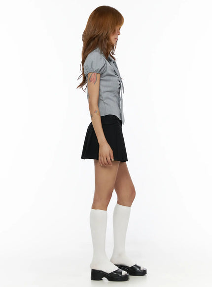 Pleated Mini Skirt CL503 Black full side shot on model styled with grey striped blouse looking down white knee socks and black platform sandals