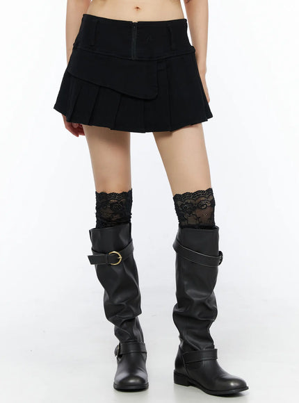 LEWKIN Pleated Mini Skirt CU530 Black front view on model wearing black boots and lace socks, layered flap detail with center back zipper