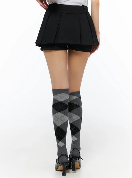Pleated Mini Skirt IL523 Black back close-up on model from waist down showing rear pleats, layered shorts hem, argyle socks, and black heels