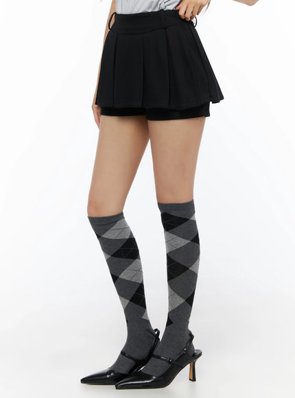 Pleated Mini Skirt IL523 Black side-view close-up on model showing pleated skirt panel, inner shorts layer, and side zipper closure detail