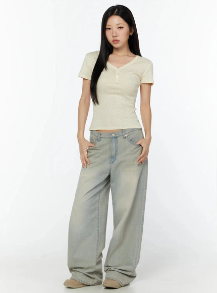 Pointelle Slim Henley V-Neck Tee IU524 Light beige full-body front shot model looking straight ahead hands in pockets showing fitted henley tee with wide-leg jeans