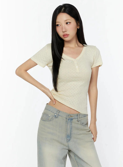 Pointelle Slim Henley V-Neck Tee IU524 Light beige three-quarter styled shot model hand on hip looking away showing fitted cropped silhouette with jeans