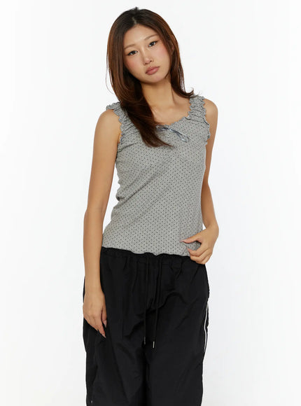 Polka Dot Frill Tank Top CL515 Gray front model three-quarter shot with ruffle straps and satin bow, paired with black track pants, hand at hip