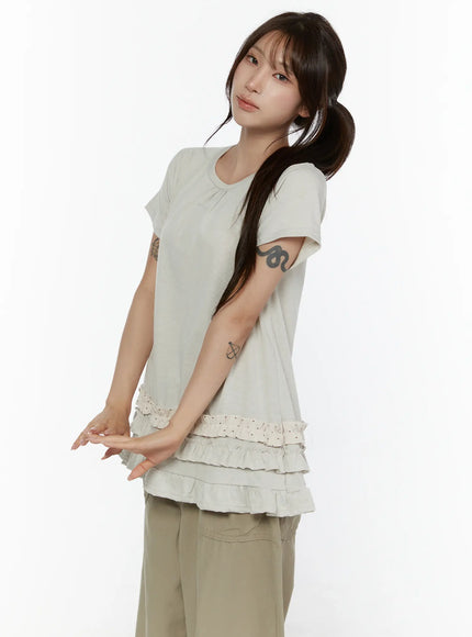 Polka Dot Frill Tee CL507 Beige side shot model in three-quarter pose showing relaxed A-line silhouette with tiered polka dot ruffle hem and khaki pants