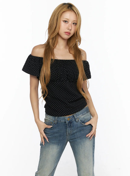 Polka Dot Frill Two-Way Tee CL528 Black close-up front shot on model showing off-shoulder neckline, ruffle frill detail, and white polka dot texture on fitted crop silhouette