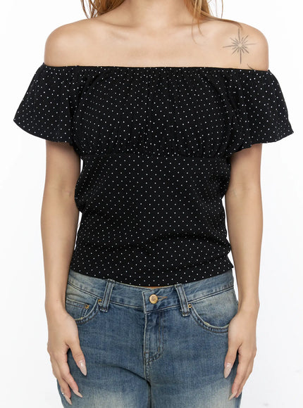 Polka Dot Frill Two-Way Tee CL528 Black front shot on model in off-shoulder style, hands on hips, showing fitted waist and white dot print with blue denim jeans
