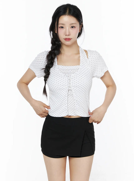Polka Dot Halter Layered Tee IU525 White front shot on model hands on hips, square cut-out halter neckline, polka dot short-sleeve crop top styled with black wrap skort