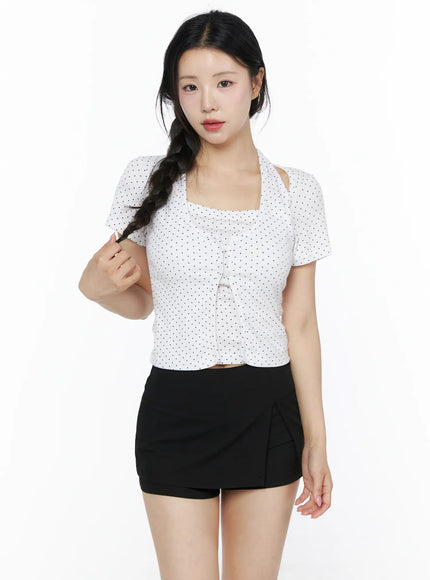 Polka Dot Halter Layered Tee IU525 White front shot on model touching braid, square cut-out halter neckline, polka dot button-front crop top paired with black mini skort