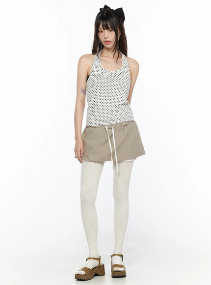 Polka Dot Halter Tank CL523 White full-length front shot on model in black dot halter tank with scoop neck styled with beige drawstring mini skirt and white patterned tights