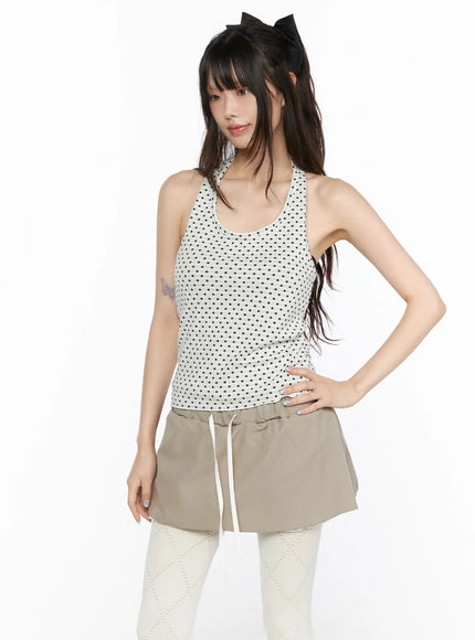 Polka Dot Halter Tank CL523 White front shot on model hand on hip wearing black dot halter racerback tank with fitted silhouette styled with beige drawstring mini skirt