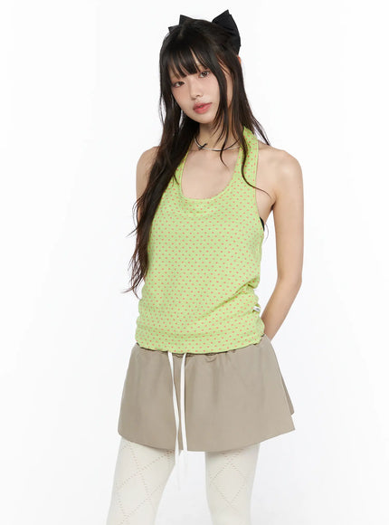 Polka Dot Halter Tank CL523 Green front shot on model wearing lime green top with pink polka dots racerback halter neck styled with beige mini skirt and white tights
