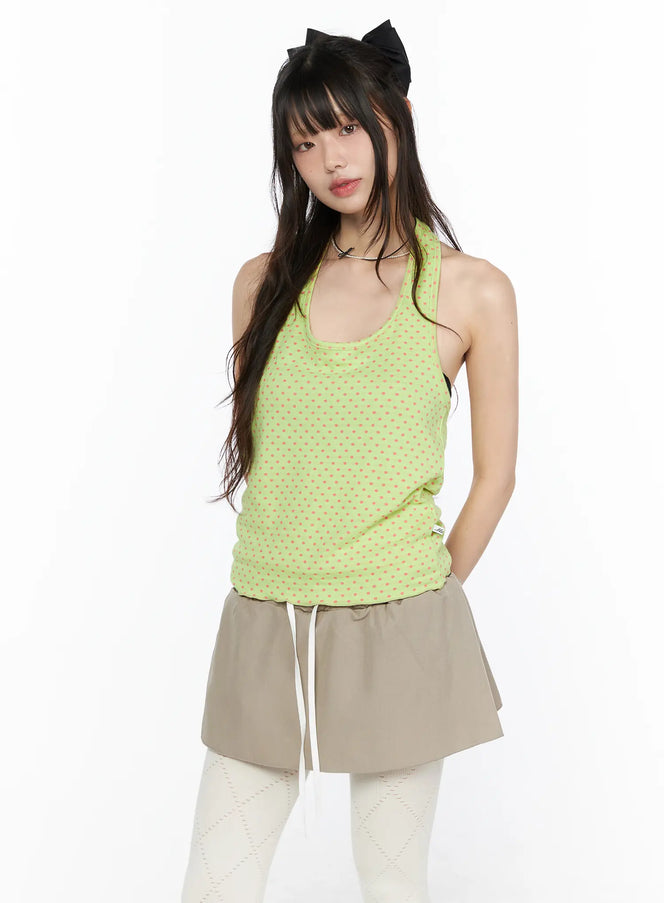 Polka Dot Halter Tank CL523 Green front shot on model wearing lime green top with pink polka dots racerback halter neck styled with beige mini skirt and white tights