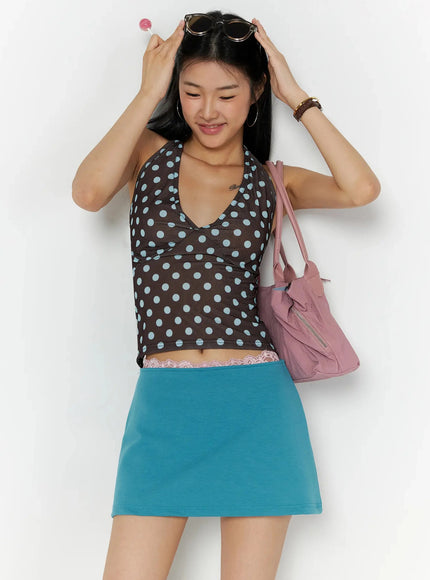 Polka Dot Halter Top IL509 Brown front lifestyle shot on model arms raised smiling, deep V-neck halter with blue polka dots, styled with teal skirt