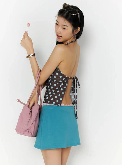 LEWKIN Polka Dot Halter Top IL509 Brown back shot on model holding lollipop with pink bag, open-back tie detail, paired with teal mini skirt