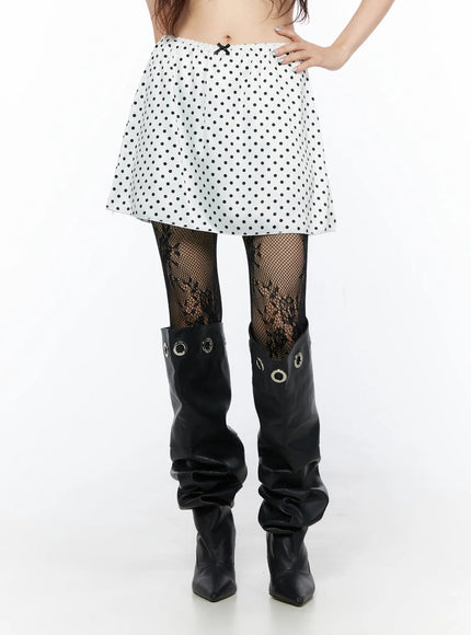 Polka Dot Ribbon Satin Mini Skirt CL522 White close-up front shot on model showing black dot print elastic waistband bow detail with fishnets and tall boots
