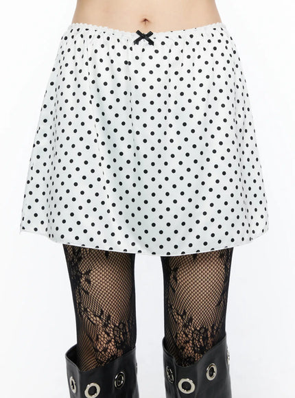 Polka Dot Ribbon Satin Mini Skirt CL522 White close-up front detail shot on model highlighting elastic waistband small black ribbon bow and polka dot satin fabric texture