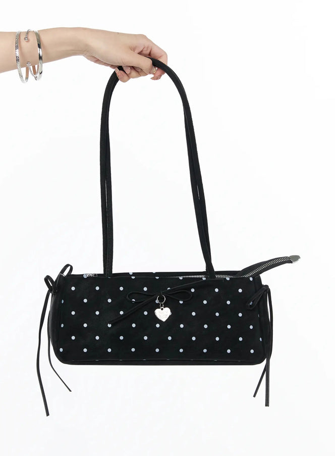 LEWKIN Polka Dot Ribbon Shoulder Bag IL523 Black hand-held shot model hand gripping dual straps of cylindrical polka dot bag with bow charm and side tie details