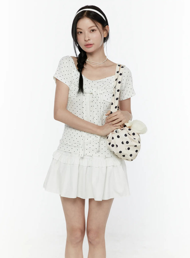 LEWKIN Polka Dot Round Shoulder Top IL506 White S/M front model shot with braided hair, square neckline, black polka dot tie-front top styled with white ruffle mini skirt and polka dot bag