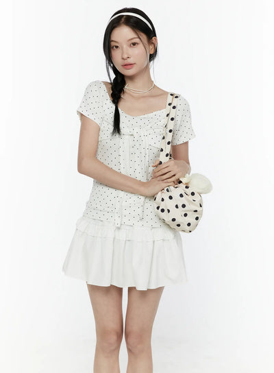 LEWKIN Polka Dot Round Shoulder Top IL506 White S/M front model shot with braided hair, square neckline, black polka dot tie-front top styled with white ruffle mini skirt and polka dot bag