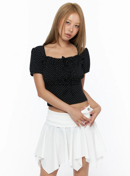 Polka Dot Shirred Puff Sleeve Top CU524 Black three-quarter front view model holding white accessory square neckline ruched polka dot crop top