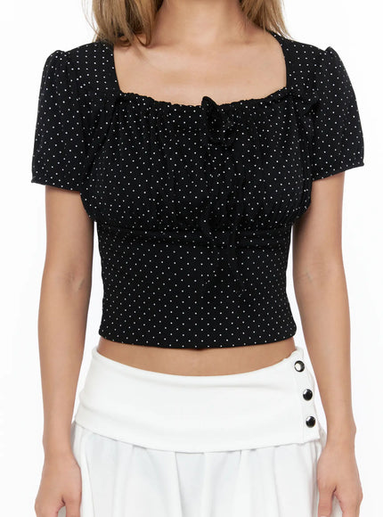 Polka Dot Shirred Puff Sleeve Top CU524 Black close-up front detail view square neckline ruched tie bow and white polka dot texture on model