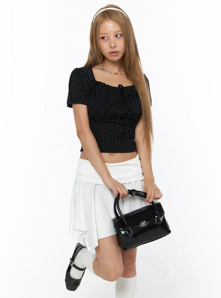 Polka Dot Shirred Puff Sleeve Top CU524 Black model kneeling pose holding black bag pearl necklace headband polka dot shirred crop top