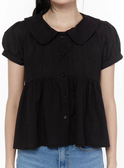 Puff Sleeve Blouse IL506 Black close-up front shot on model highlighting rounded peter pan collar, button placket, gathered peplum seam, and textured fabric detail