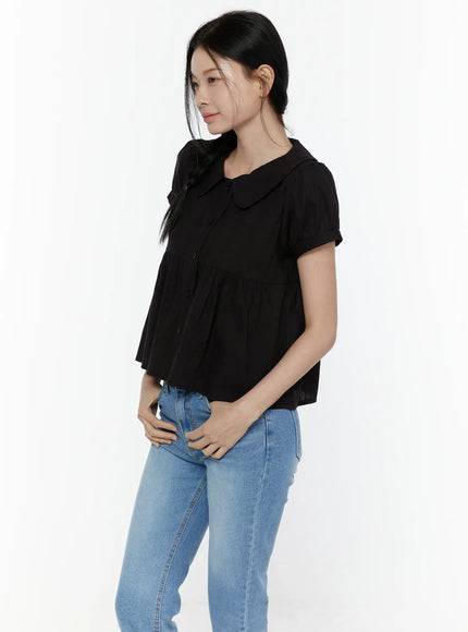 Puff Sleeve Blouse IL506 Black side shot on model showing peter pan collar spread, gathered puff sleeves, and flared peplum body with textured woven fabric