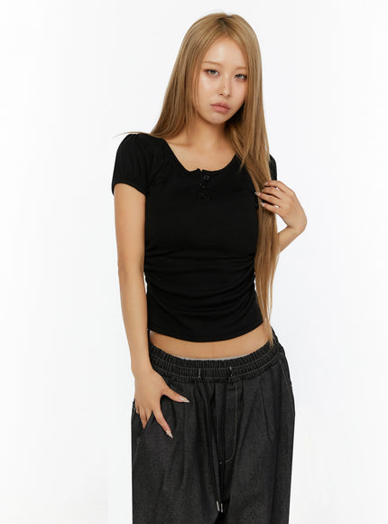 Puff Sleeve Henley Tee IL524 Black front shot on model touching hair showing fitted ribbed crop silhouette with puff cap sleeves and henley buttons